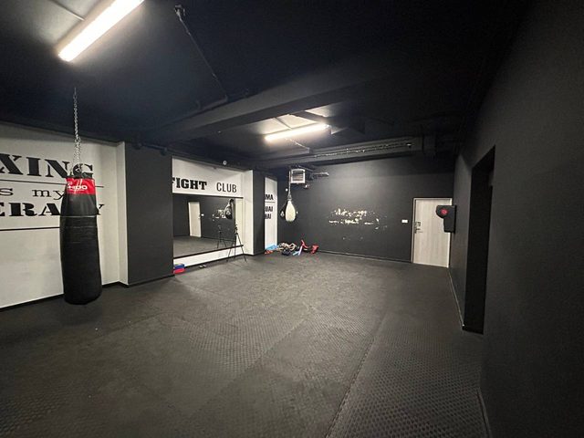 Sala treningu walki z workiem bokserskim i napisem Fight Club na ścianie